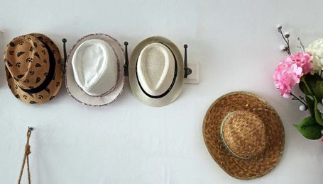4 chapeaux de paille sur mur blanc